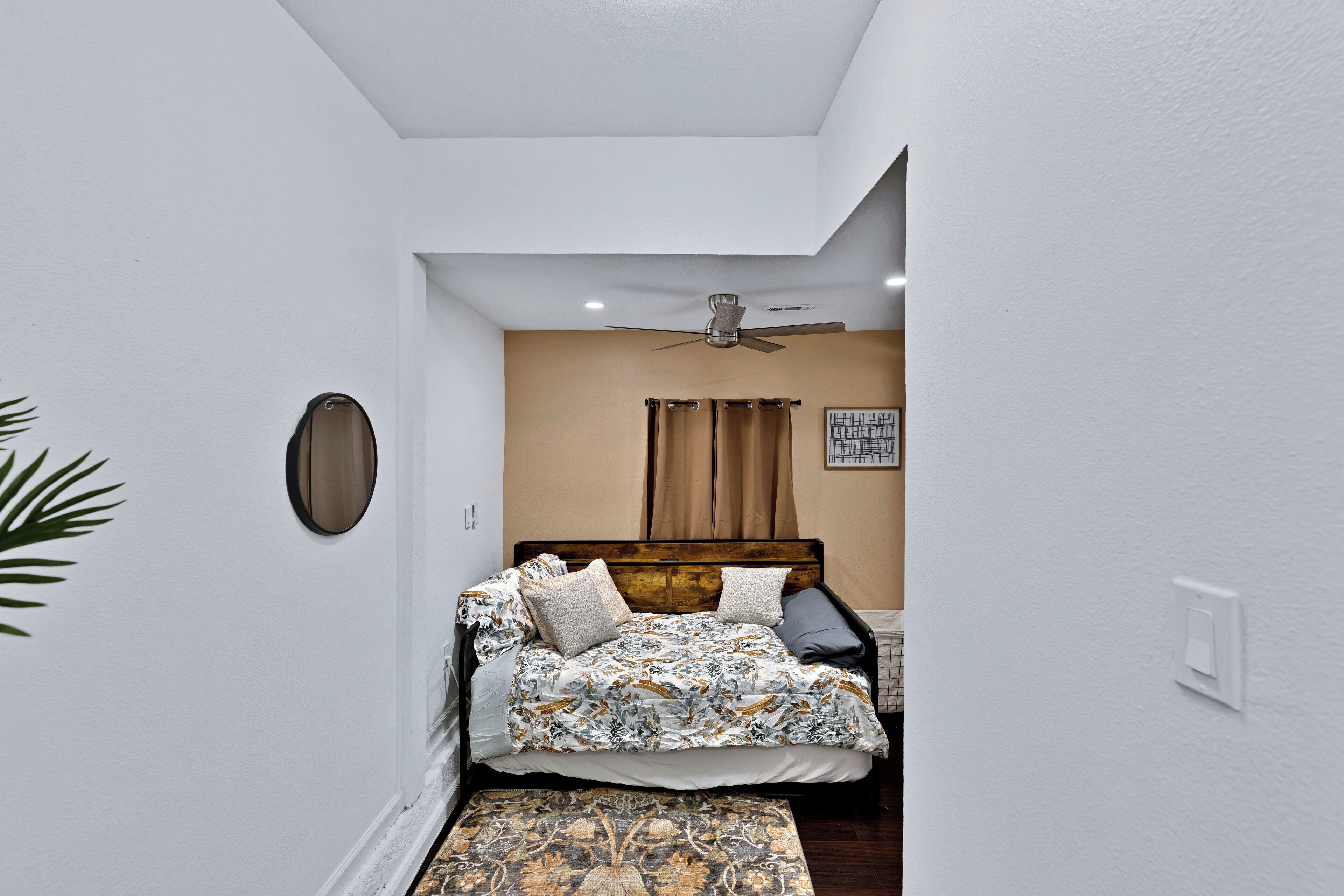 Een slaapkamer met een bed, plafondventilator en een kleed.