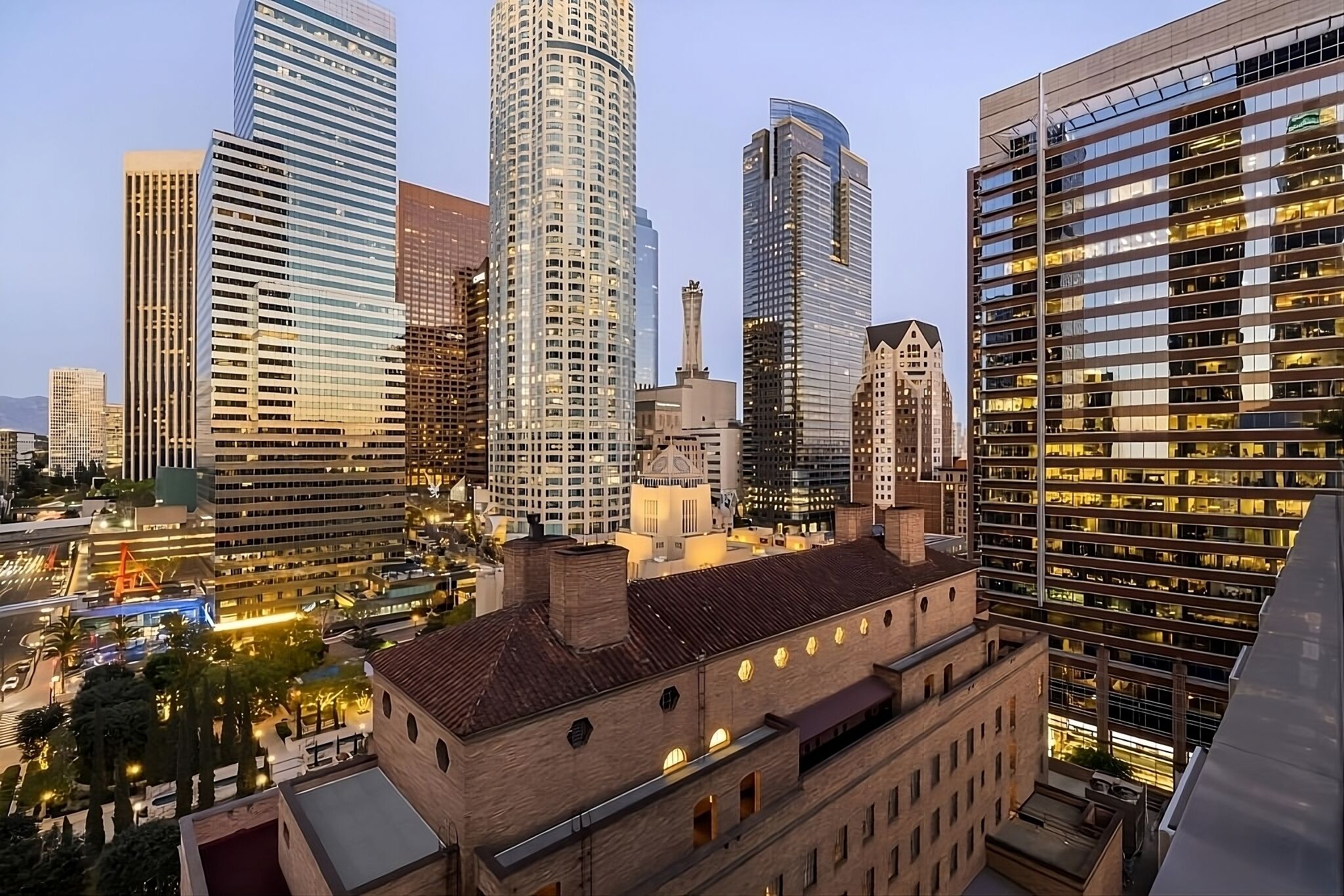 Un paysage urbain avec des immeubles modernes de grande hauteur, un bâtiment historique doté d’un toit rouge et un ciel dégagé.