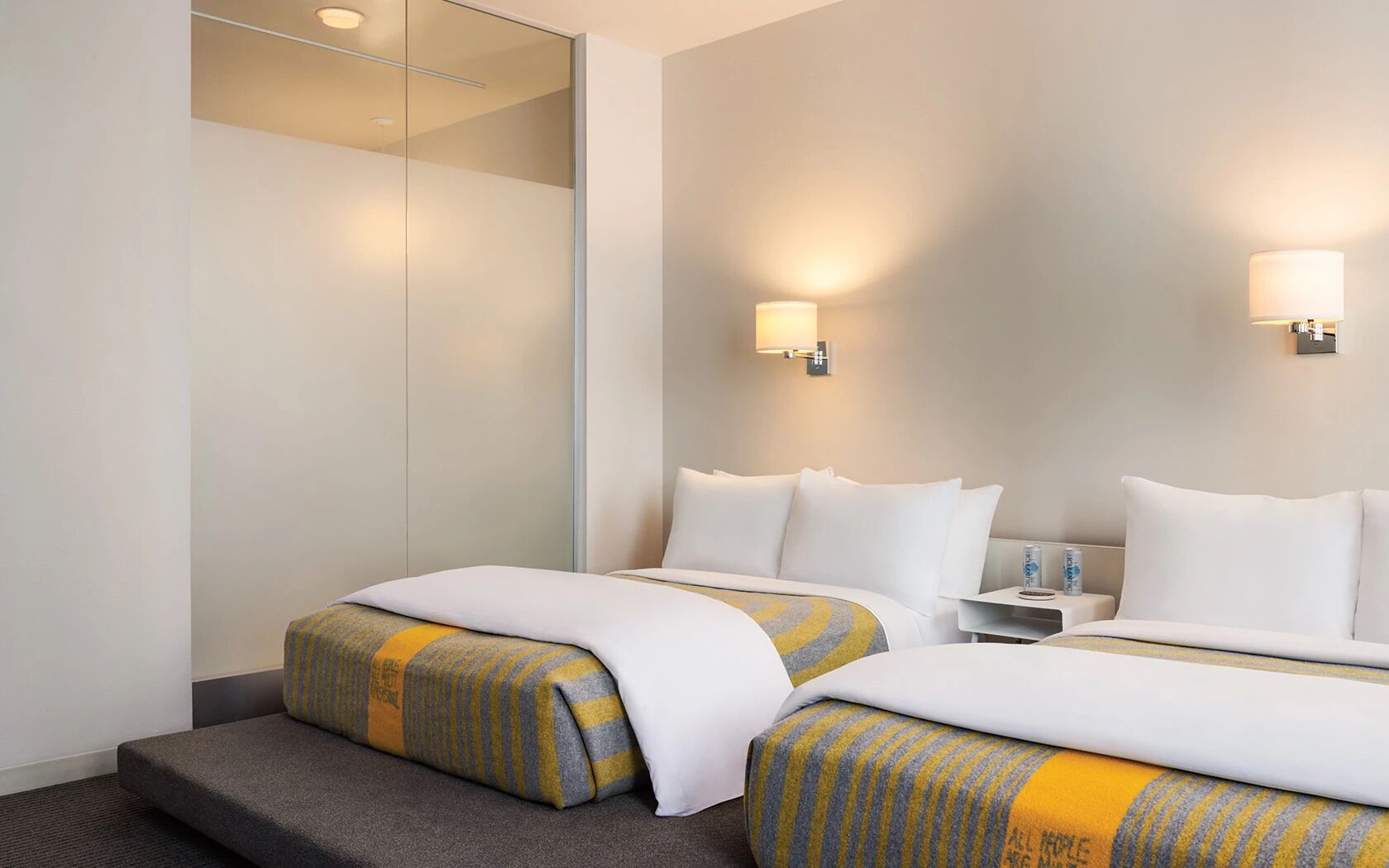 Una habitación de hotel con dos camas, una mesita de noche y una mesilla.
