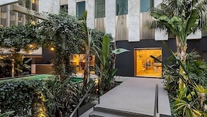 A modern indoor atrium with a central staircase, surrounded by lush greenery and a warm ambient light. - Cozy Room in DTLA w/ Restaurant & Chic Lounge Spot (Los Angeles)