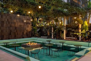 An outdoor seating area with a fire pit, green cushioned seating, and tables. - Save in 2 Units w/ Double Size Bed Each Room (Los Angeles)