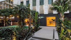 A modern indoor atrium with a central staircase, surrounded by lush greenery and a warm ambient light. - Save in 2 Units w/ Double Size Bed Each Room (Los Angeles)