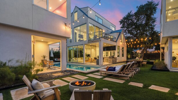 Una casa moderna con piscina, area relax esterna e luci decorative.