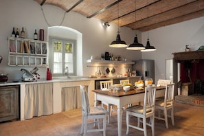 Una cucina con isola centrale, sedie bianche e lampade a sospensione.