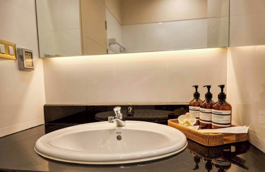 A bathroom with a white sink, a mirror, and toiletries.