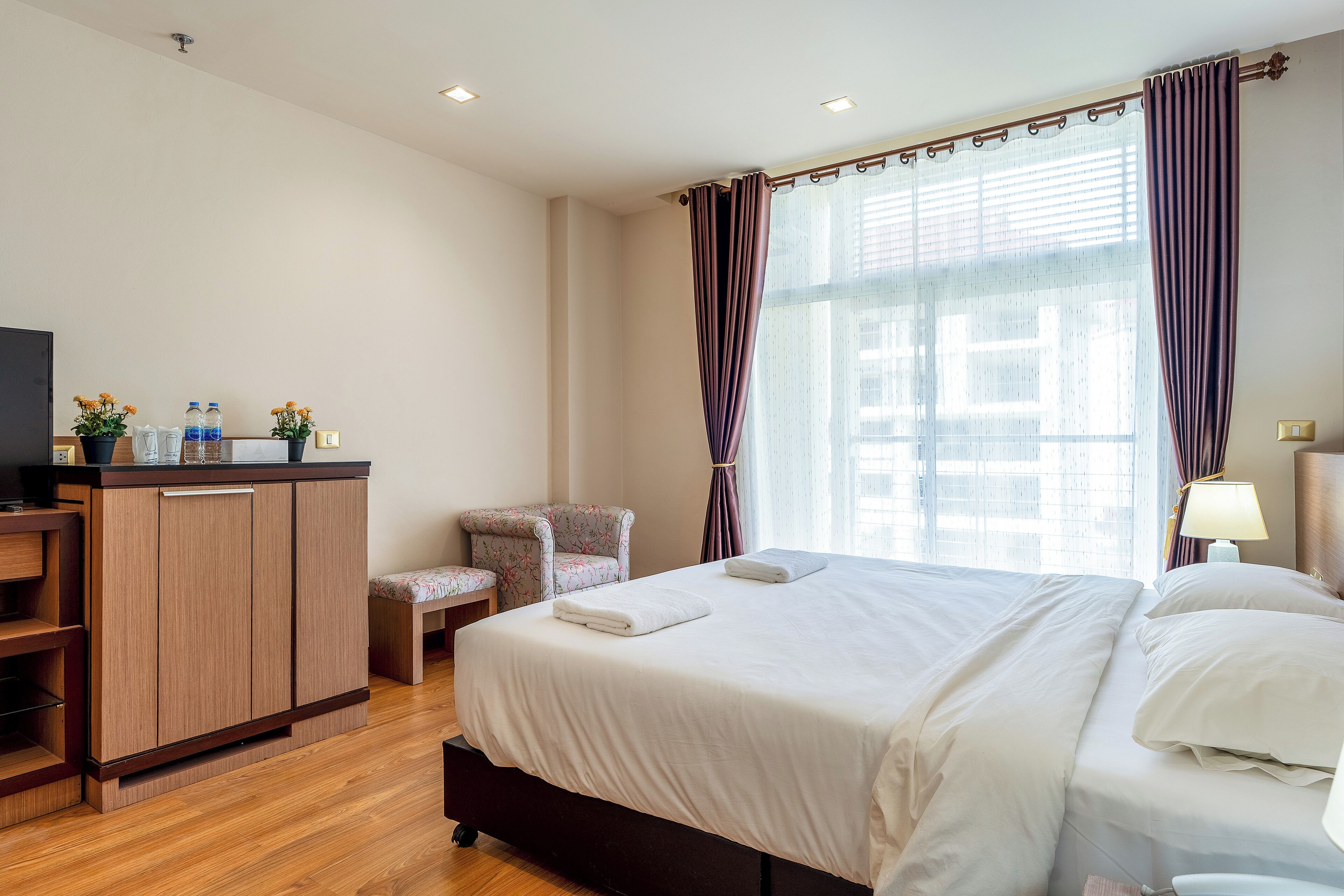 A hotel room with a bed, a desk, a chair, and a window with curtains.