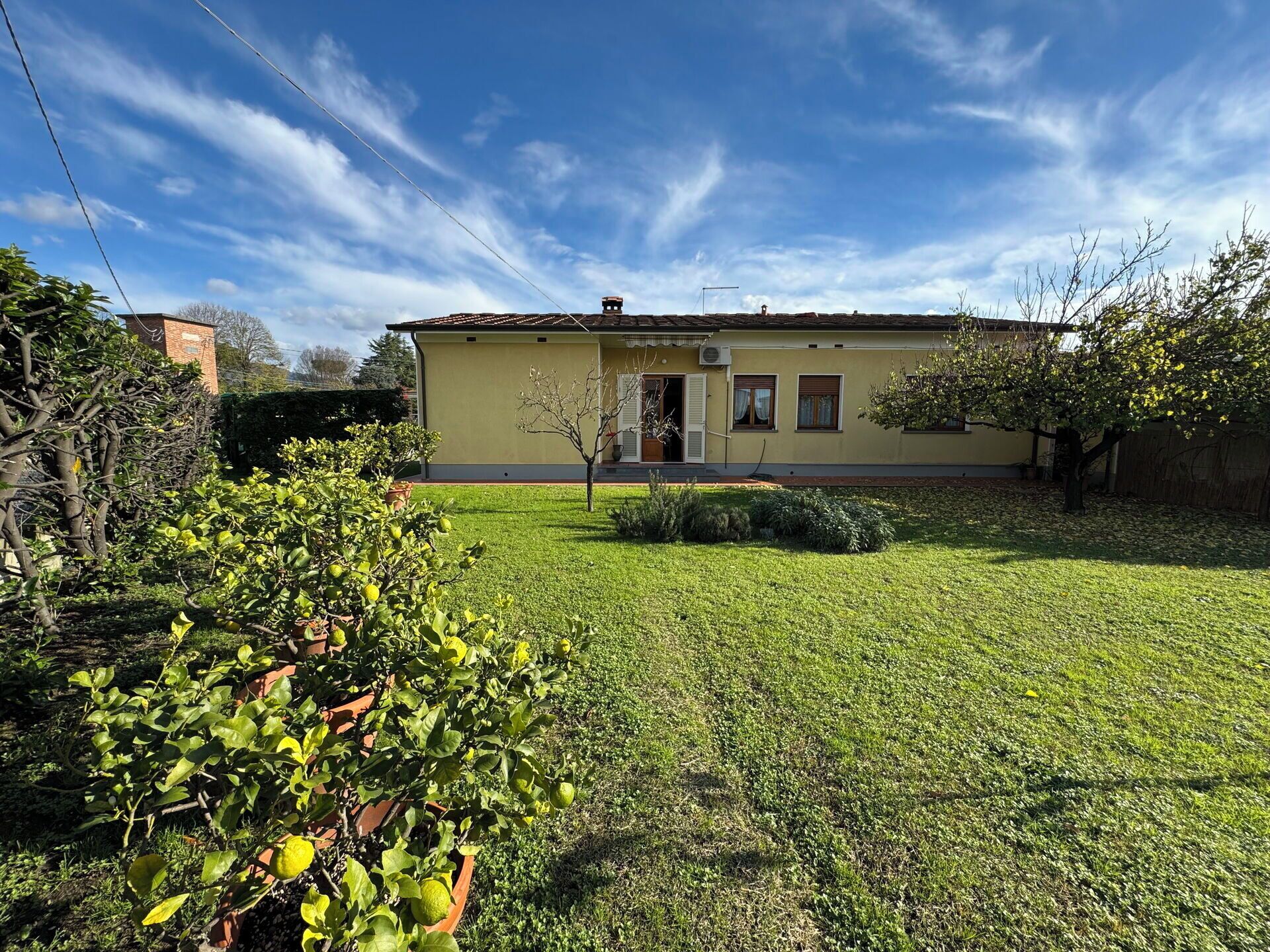 Une maison de plain-pied avec un toit plat, un petit jardin devant et un ciel dégagé.