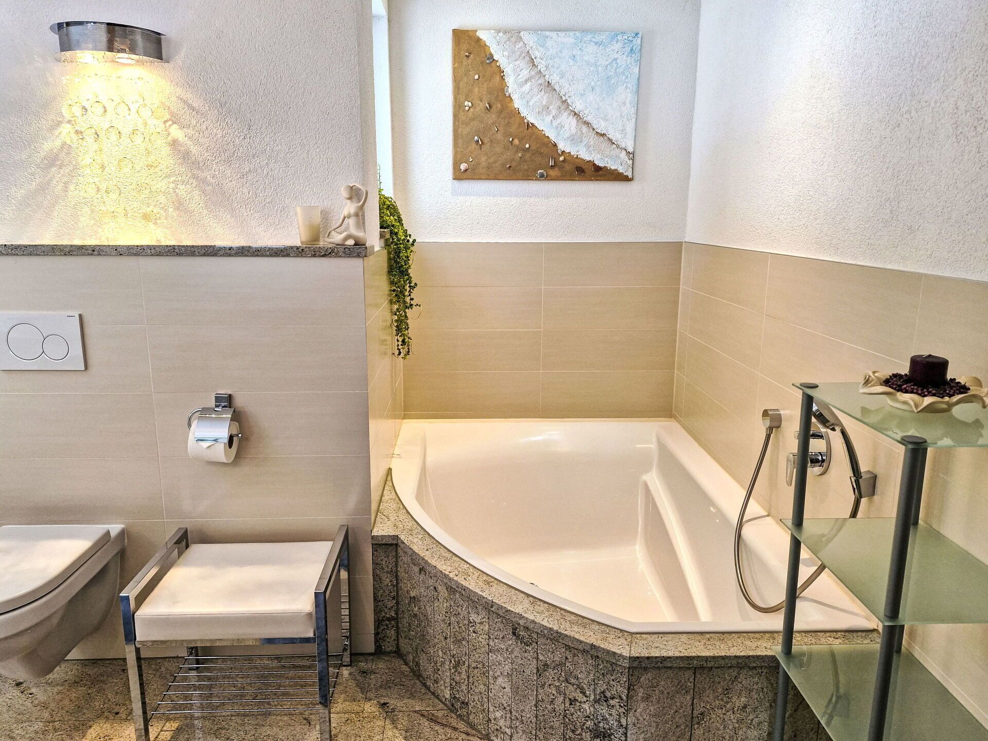 A modern bathroom with a bathtub, a glass shelf with a candle, and a wall-mounted artwork.