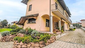 Une maison à deux étages avec un balcon, un jardin aménagé avec des pierres et une allée pavée.
