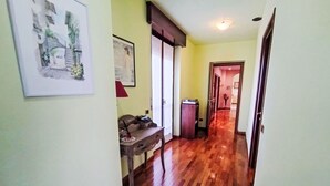 Un couloir doté d’un plancher en bois, un bureau avec un téléphone et une porte donnant sur une autre pièce.