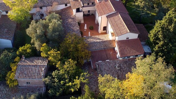Vista aérea de una villa tradicional con varias construcciones, rodeada de exuberante vegetación y árboles.