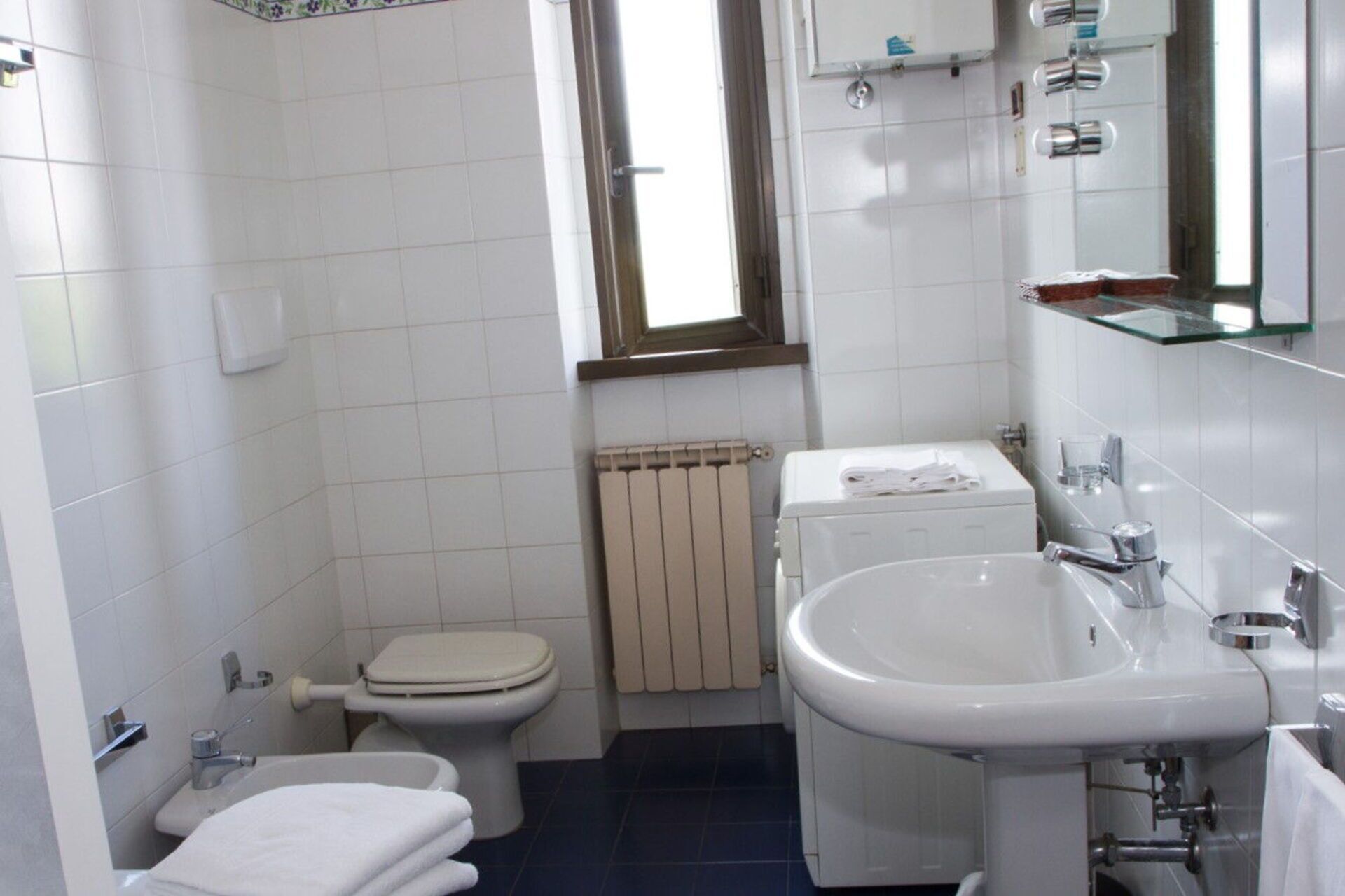 A small, clean bathroom with a toilet, sink, and a radiator.