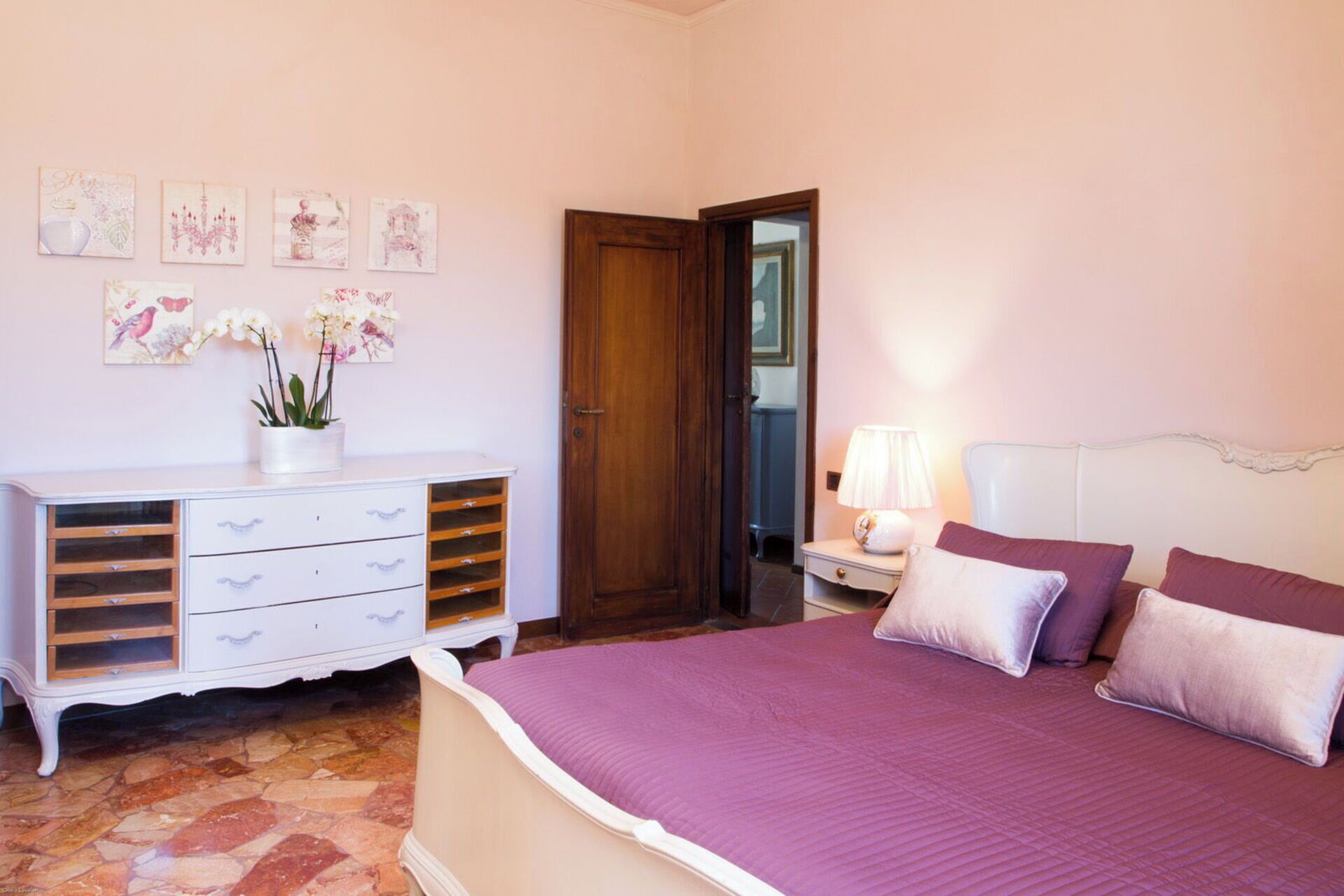 A bedroom with a bed, dresser, and artwork on the wall.