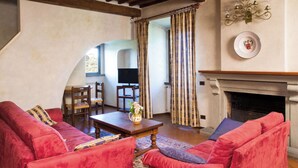 A cozy living room with red sofas, a wooden coffee table, and a fireplace. - Cosy apartment for 6 guests with pool, WIFI, A/C, TV and pets allowed, close to Florence (Impruneta)