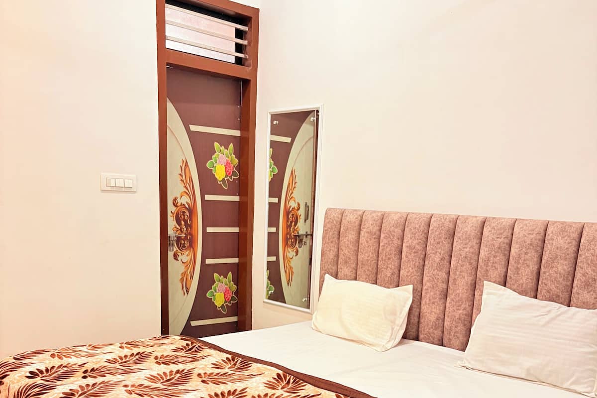 Une chambre à coucher comprenant un lit, une tête de lit, une table de chevet et une porte ornée d’un panneau décoratif.