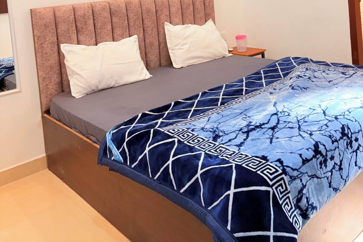 Une chambre à coucher avec un lit, deux oreillers, une table de chevet, un climatiseur et une fenêtre donnant sur un beau paysage.