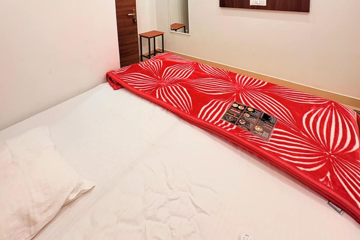 Une chambre à coucher comprenant un lit, un ventilateur de plafond, un appareil de climatisation, un miroir et une armoire en bois.