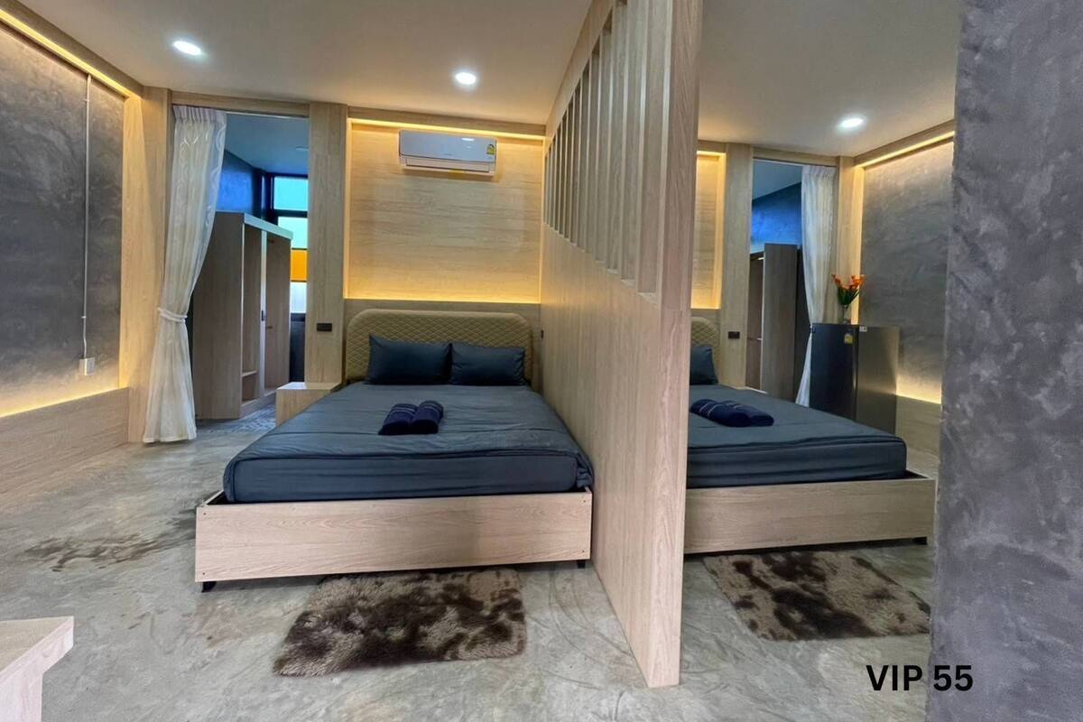 A modern hotel room with a large bed, a small desk, and a built-in air conditioning unit.