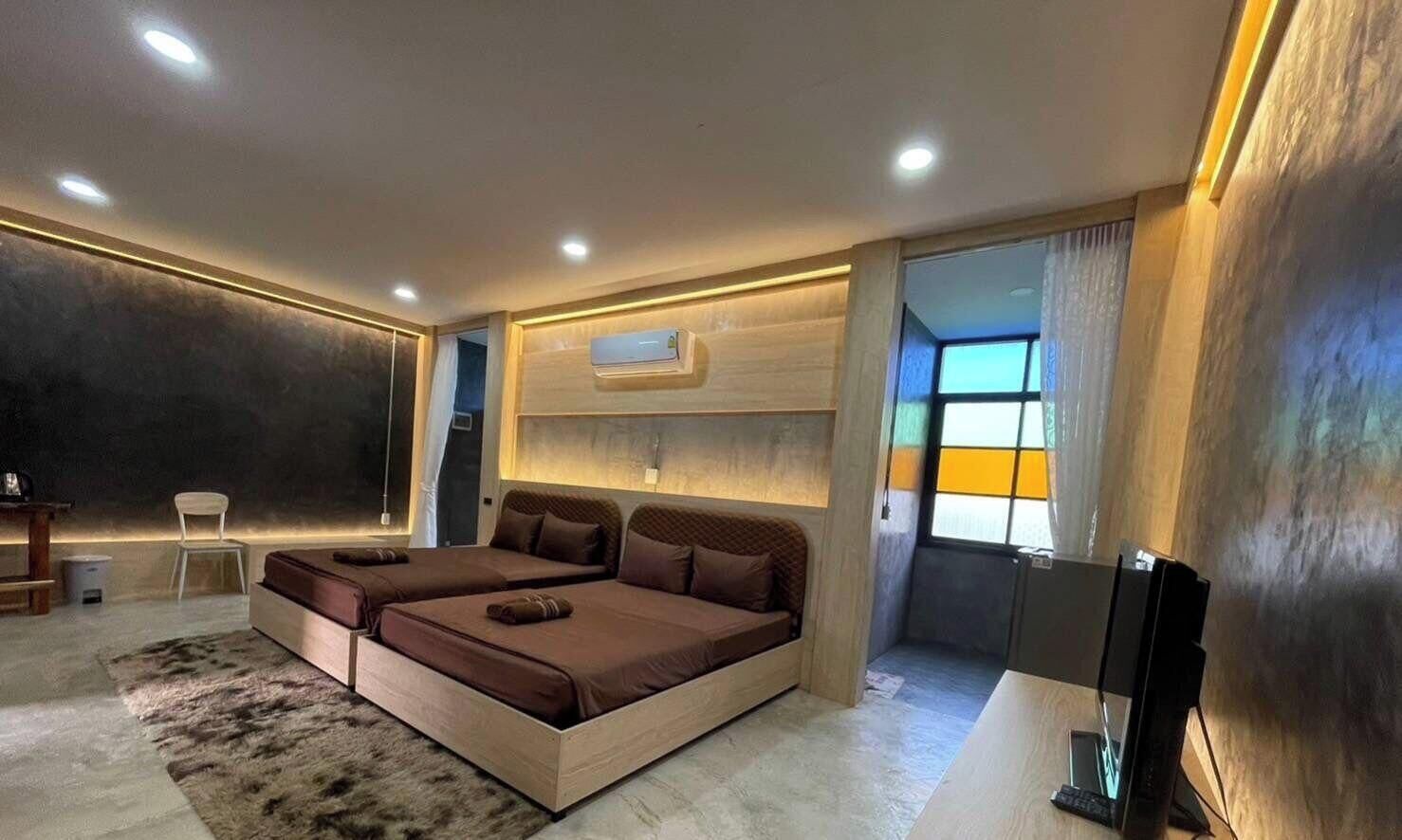 A modern bedroom with a large bed, a desk, and a window with curtains.