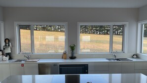 A modern kitchen with two sinks, a dishwasher, and a large island with a cutting board and candle.