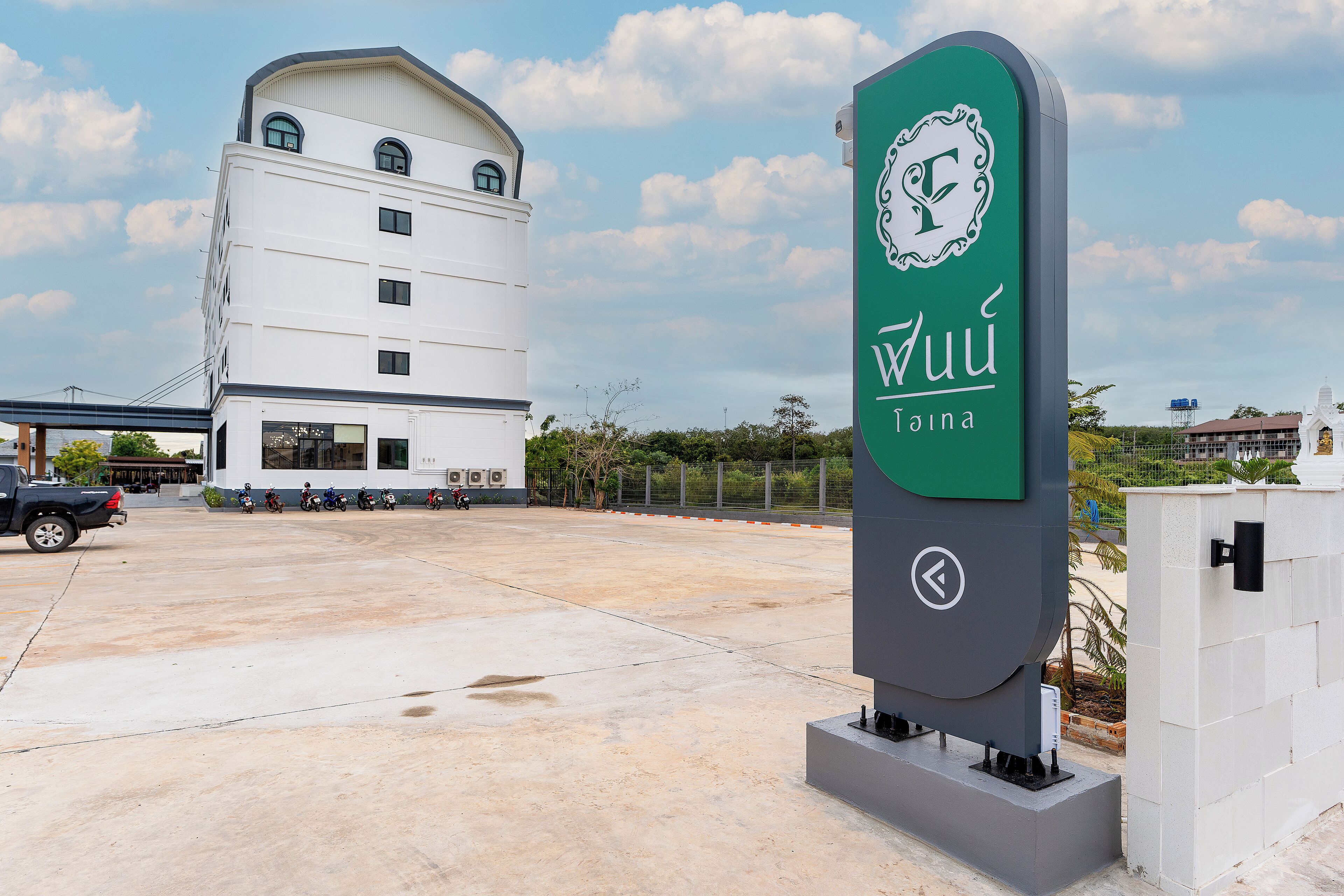 A modern building with a large sign, a parking area, and a clear sky.