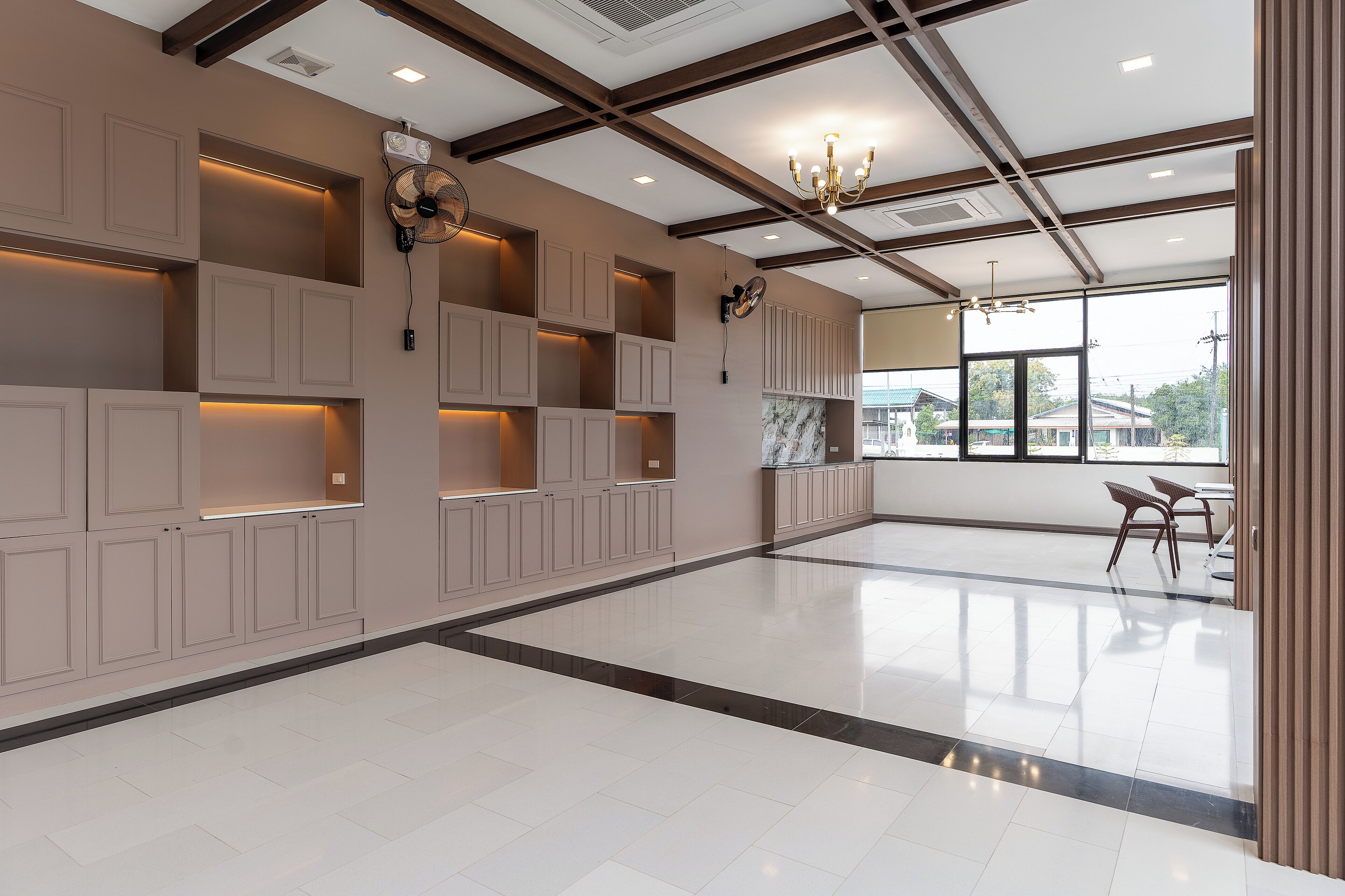 A spacious hotel lobby with high ceilings, built-in shelving, and a large window offering a view of the outside.