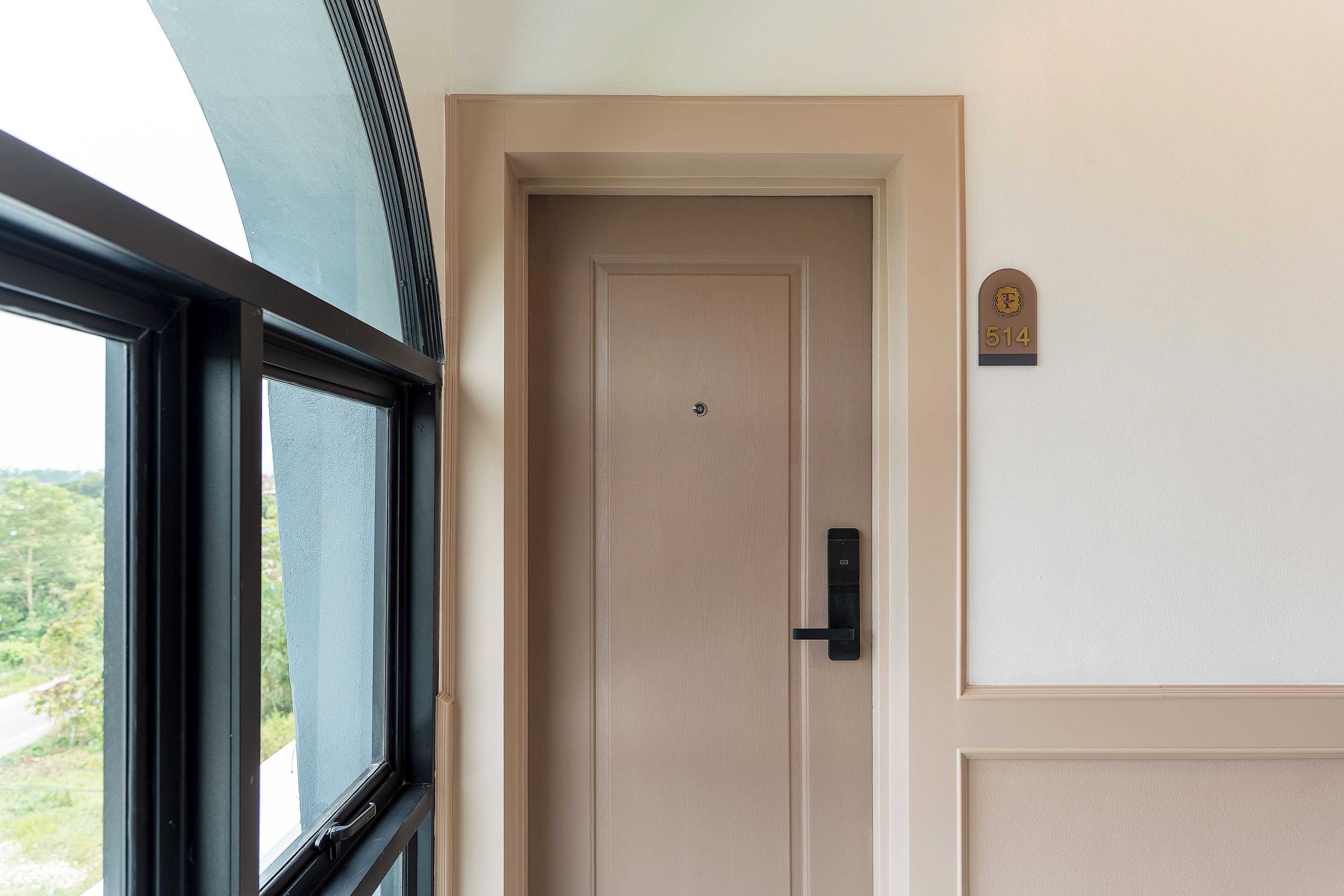 Une porte avec une plaque portant un numéro, une fenêtre et une vue sur la verdure à l’extérieur.
