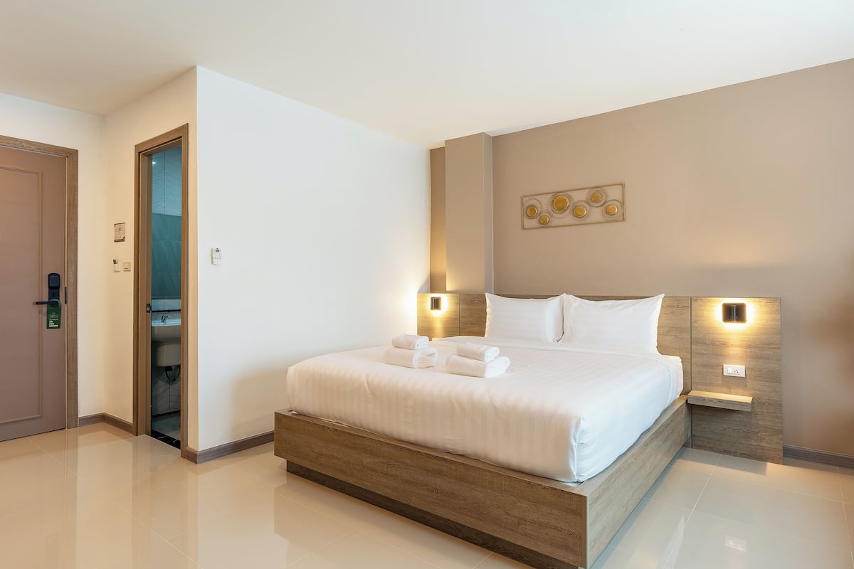 Een moderne hotelkamer met een groot bed, nachtkastjes en een zichtbare badkamer door een open deur.