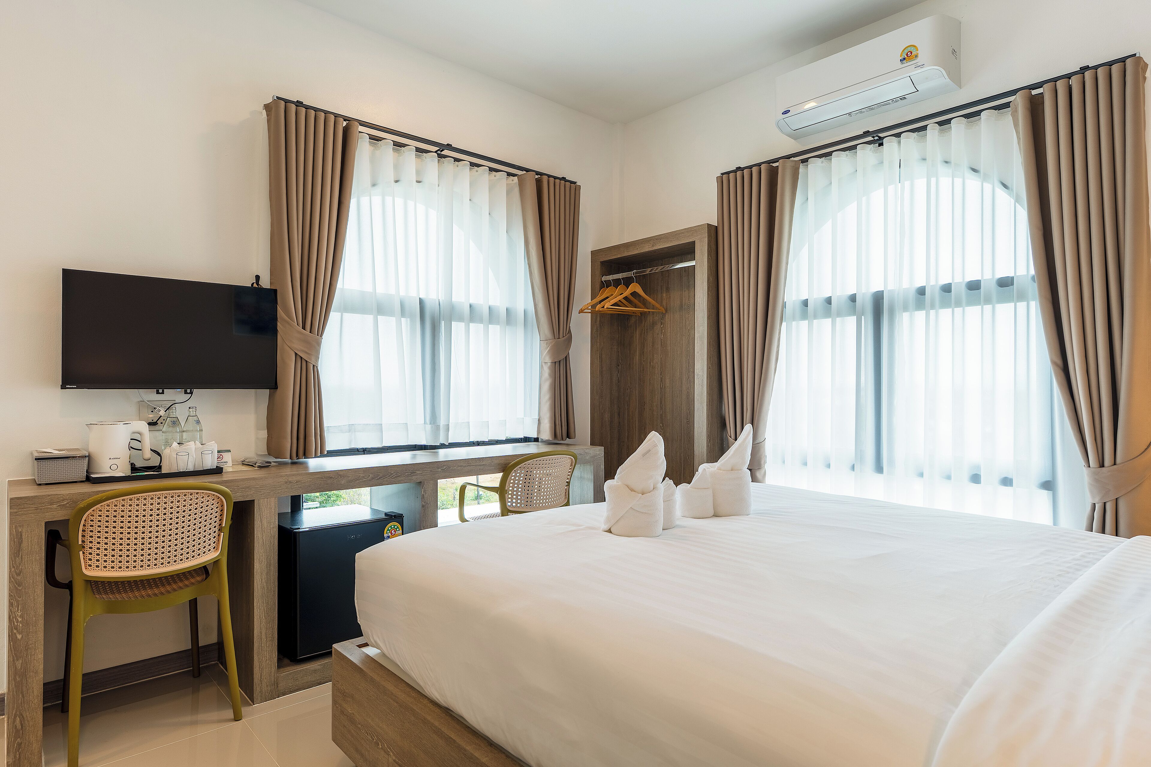 Una habitación de hotel con cama, escritorio, silla, televisor y armario.