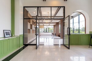 Decoração moderna com divisória de vidro, armários verdes e vista para uma varanda.
