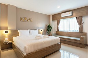 Quarto de hotel moderno com uma cama grande, mesas de cabeceira, ar condicionado e uma janela com cortinas.