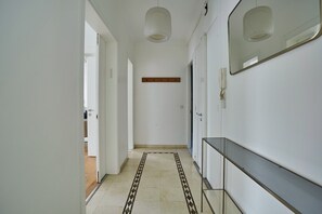 A hallway with a patterned rug, a wooden shelf, a mirror, and a glass table. - Superb apartment Center of Paris-Montmartre (Paris)
