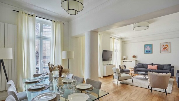 A modern living room with a glass dining table set for four, a sofa, and a TV in the background. - Superb apartment Center of Paris-Montmartre (Paris)