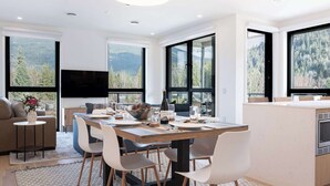 Een moderne keuken met een groot schiereiland, een eethoek met stoelen en een bank.