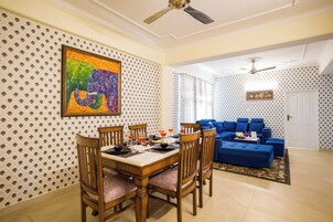 A dining area with a wooden table, chairs, and a blue sofa in the background.