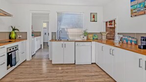 A modern kitchen with white cabinets, a wooden countertop, and a built-in dishwasher.