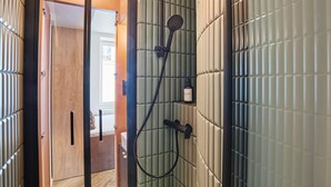 Un baño con ducha, una puerta de madera y un perchero.