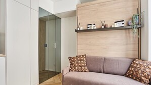 Una sala de estar moderna con un sofá, una mesa de centro y una estantería de madera con objetos decorativos.