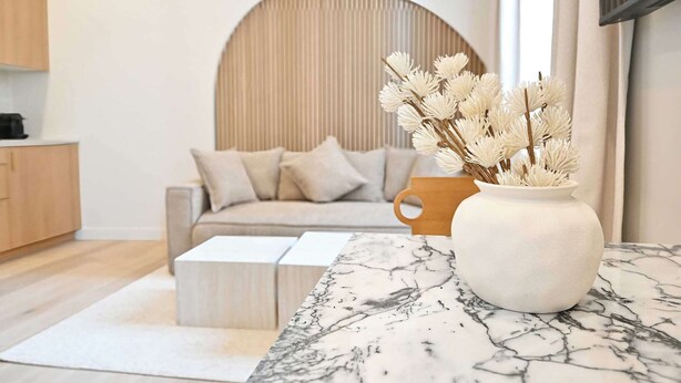 Una sala de estar moderna con un sofá, una mesa de centro y un florero con flores secas.