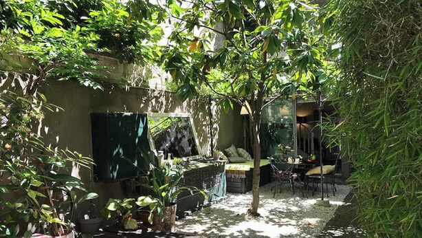 Un espace extérieur ensoleillé, aménagé avec des sièges, une petite table et des plantes en pot.