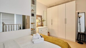 Une chambre à coucher moderne avec un lit, une armoire, un bureau et un miroir.
