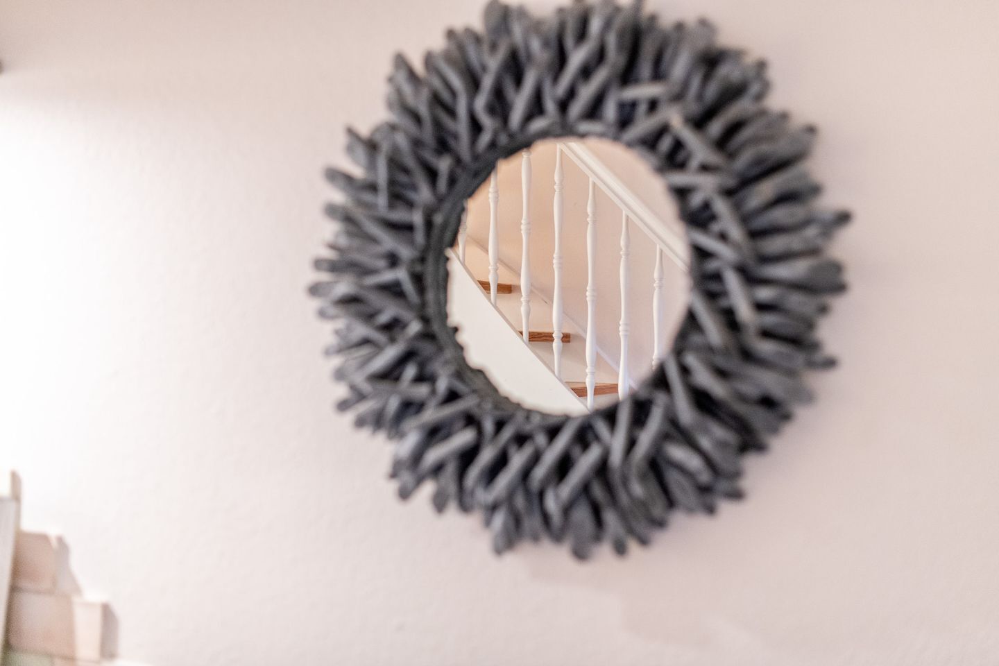 A wall-mounted mirror with a circular, textured frame.