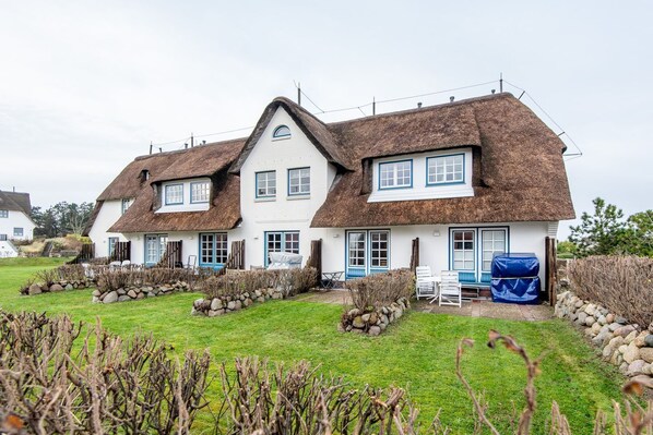 A traditional thatched-roof house with a white exterior and blue trim. - Raantem Hüs, Whg. 12 Lütte Perle (Sylt)