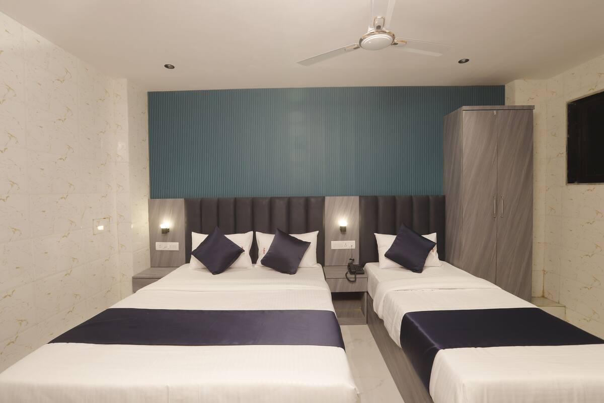 Habitación de hotel con dos camas, un armario, un ventilador de techo e iluminación en la pared.