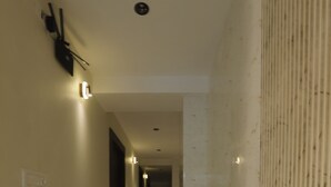 A hotel hallway with a marble floor, light fixtures on the walls, and a textured wall on the right. - Adkar Residency Gorai Borivali West  (Mumbai)