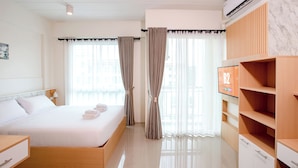 Una habitación de hotel moderna con una cama bien hecha, un televisor en la pared y un armario de madera.