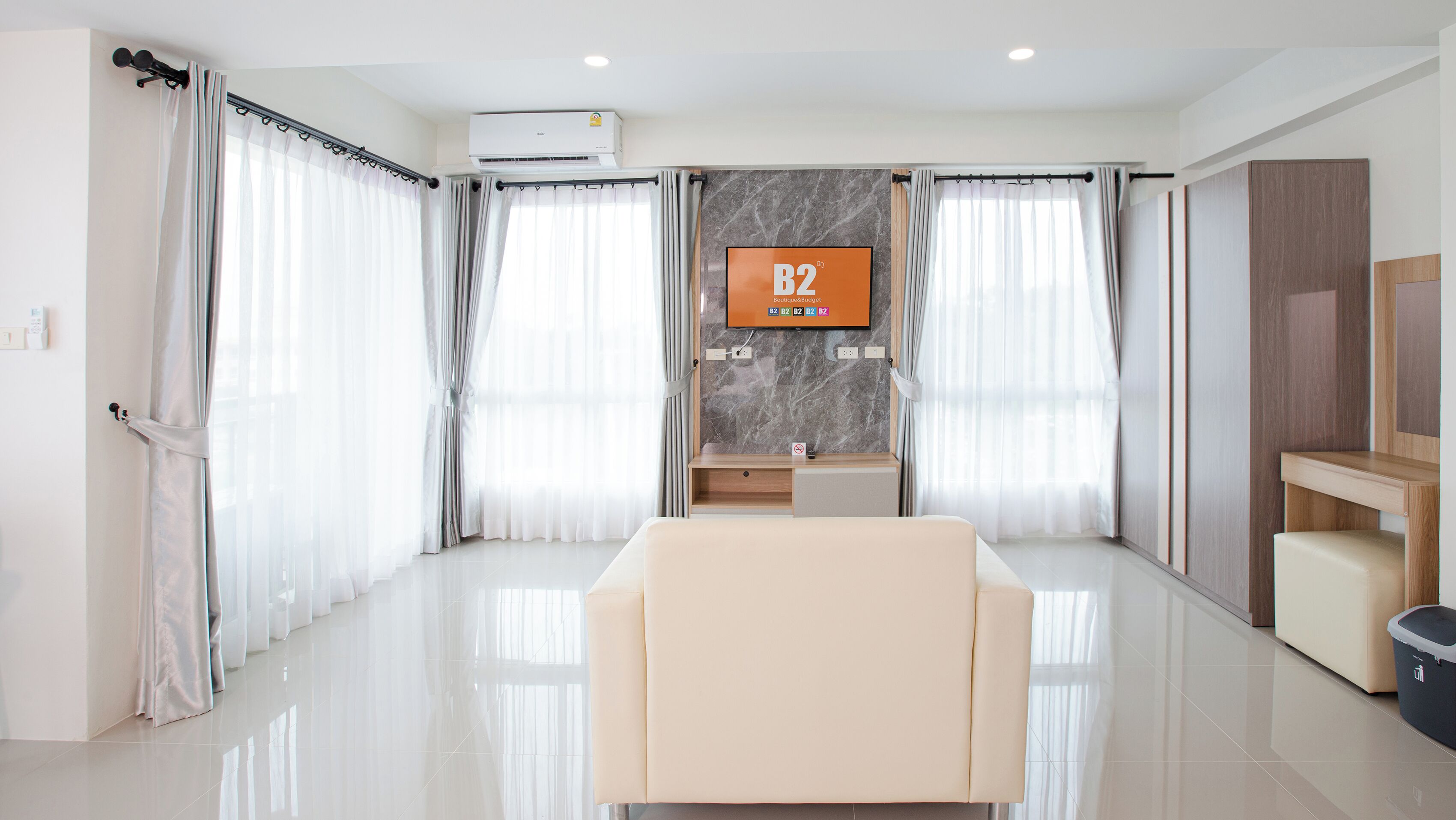 Una habitación de hotel moderna con una cama grande, un escritorio, un televisor y un baño con pared de mármol.