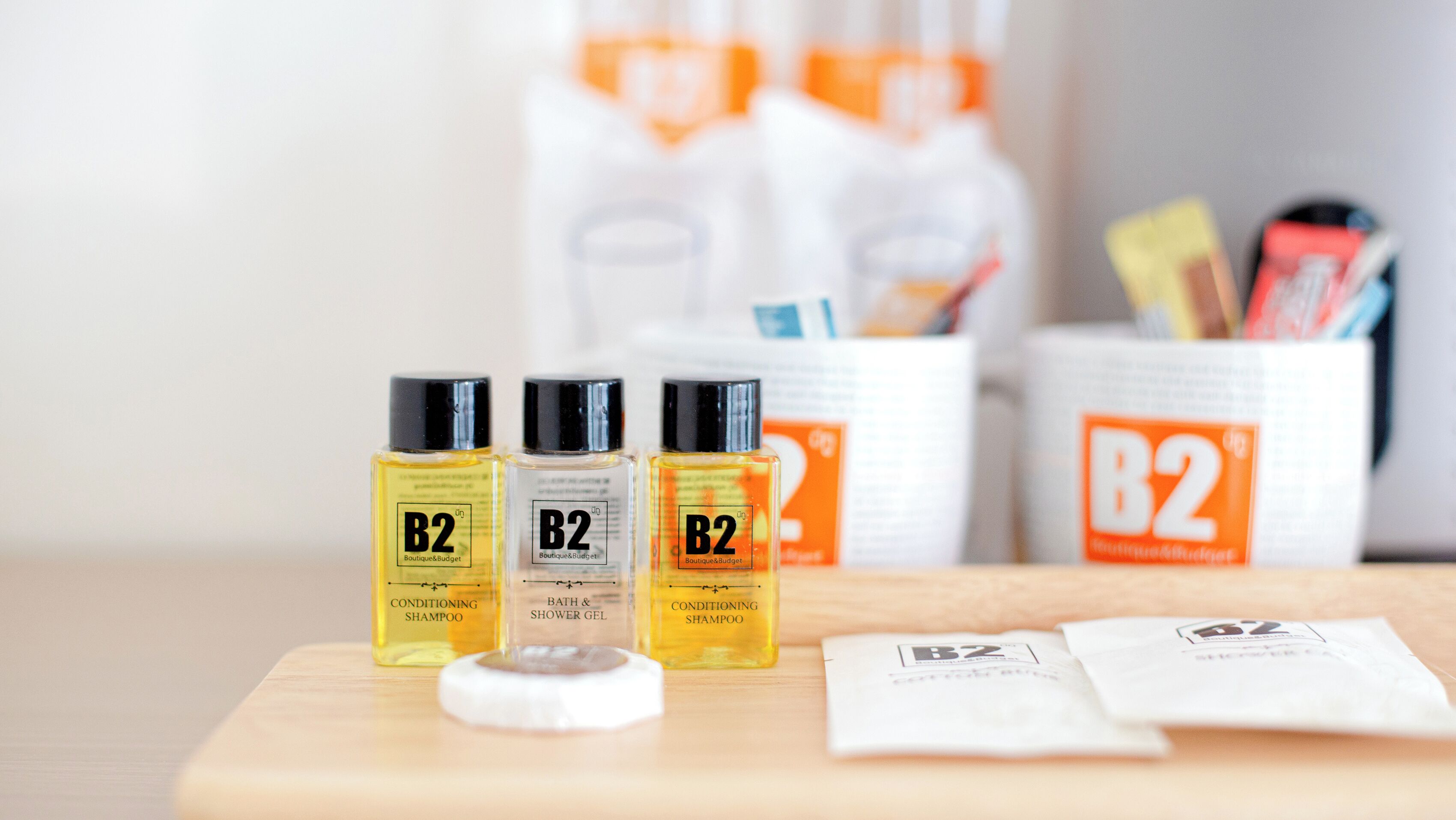 Three B2 Boutique & Budget conditioning shampoo bottles, a white cap, and some B2 branded packaging on a wooden surface.