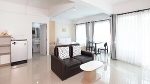 Una habitación de hotel moderna con sofá, una mesita, cama, baño y zona de comedor.
