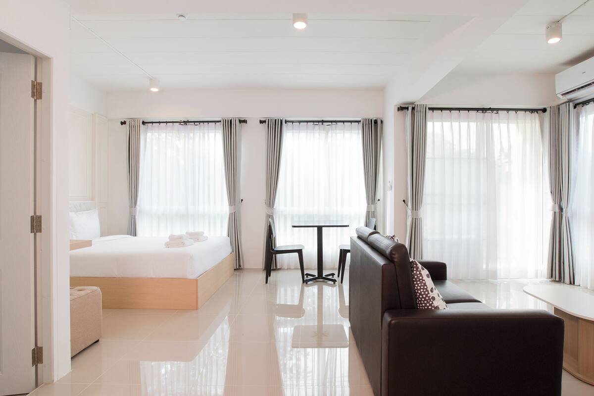 Una habitación de hotel moderna con una cama, un sofá, una mesita y una silla.